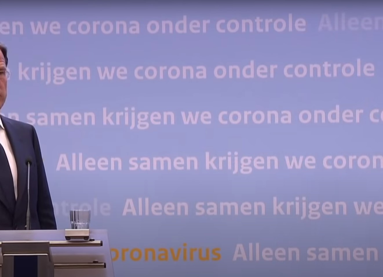 Lichtblauwe wand met tekst achter minster-president Rutte