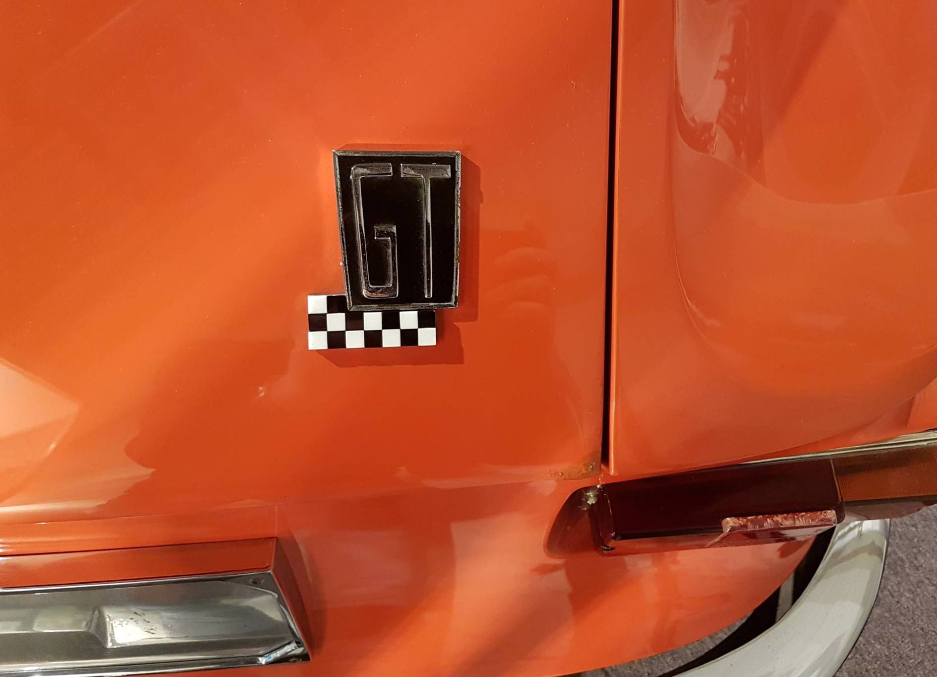 Oranje plaatwerk met een badge bestaande uit de letters GT en een 'chequered flag'.