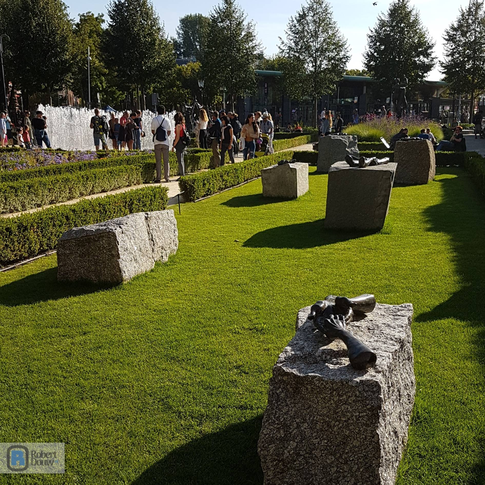 Overzicht van de tuin met granieten blokken waar de bronzen handen op liggen.